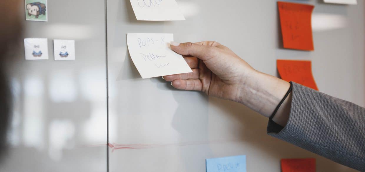En person lägger post-it lappar på en tavla